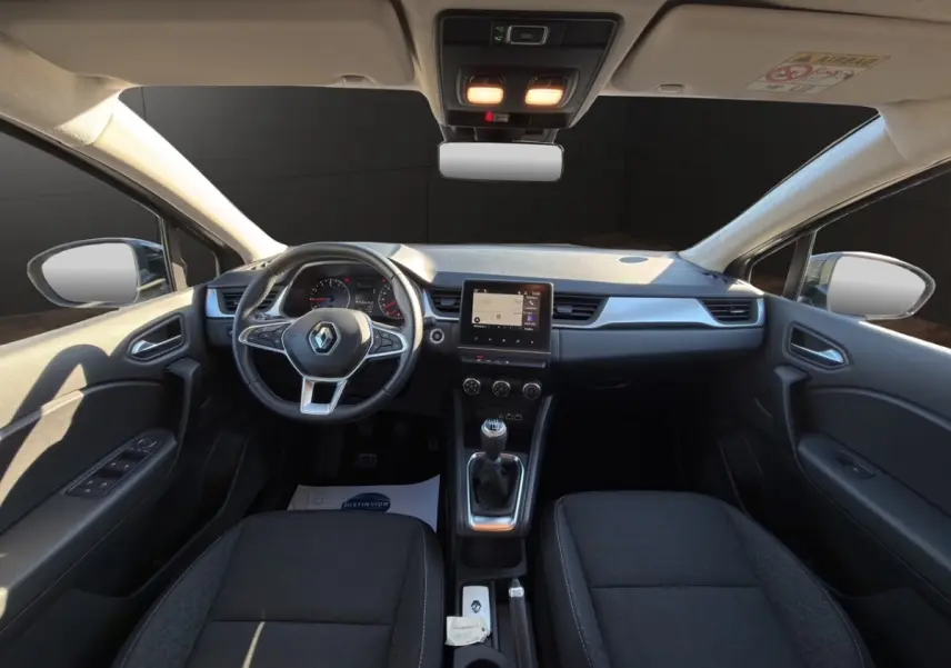 Vue intérieure avant du Renault Captur gris foncé 2024, tableau de bord avec écran tactile et volant multifonctions cuir synthétique.