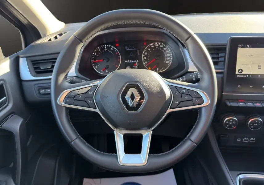 Vue centrée sur le volant cuir du Renault Captur 2024 avec tableau de bord et écran tactile de navigation visible.