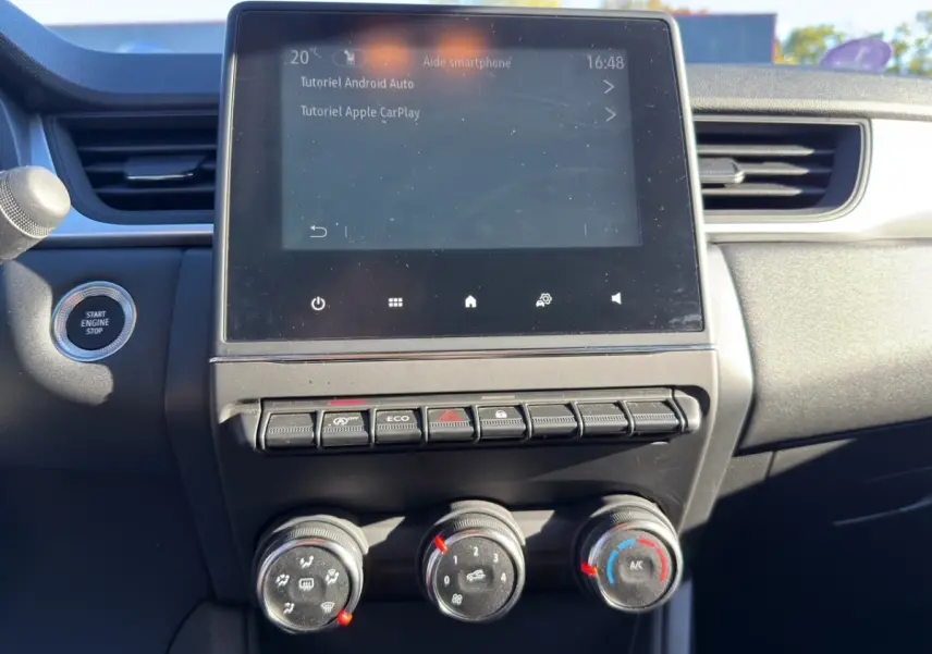 Vue rapprochée de la console centrale du Renault Captur gris foncé 2024, écran tactile et commandes climatisation visibles.
