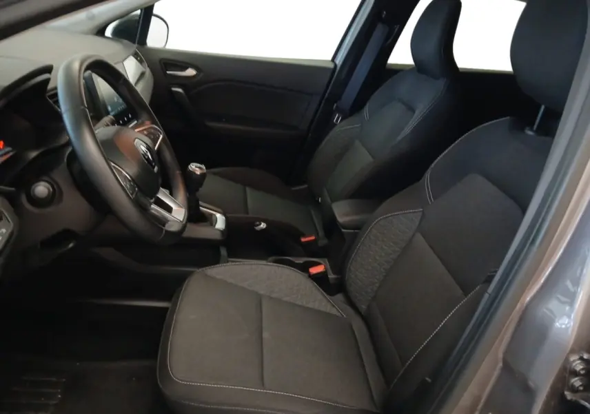 Intérieur avant droit du Renault Captur gris foncé 2024, sièges tissu noirs et volant multifonctions cuir synthétique.