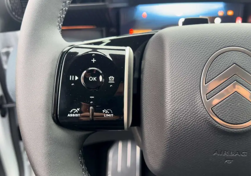 Gros plan sur les commandes multifonctions à gauche du volant cuir gris du Citroën C5 Aircross Hybrid 2026.
