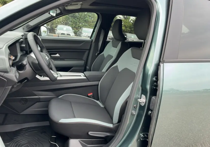 Vue intérieure côté conducteur du Dacia Bigster vert cèdre, montrant les sièges bi-ton et le volant cuir soft feel.