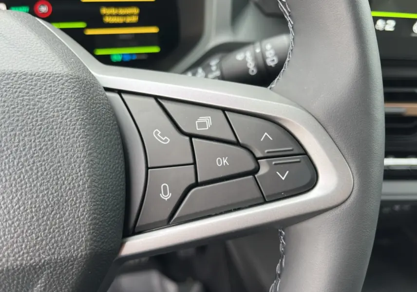 Gros plan sur les commandes au volant cuir du DACIA BIGSTER Hybrid 155 Extreme Plus, intérieur moderne et fonctionnel.