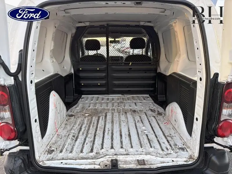 Vue arrière ouverte du Citroën Berlingo blanc montrant l’espace de chargement avec cloison tubulaire noire.