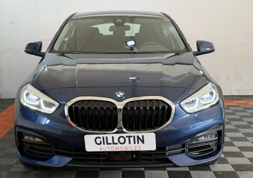 Vue avant d'une BMW Série 1 116i Business Design bleu avec calandre double haricot et phares LED allumés.