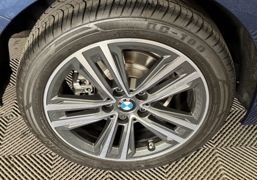 Gros plan sur la jante alliage BMW de la Série 1 bleu, avec logo central et pneu visible.