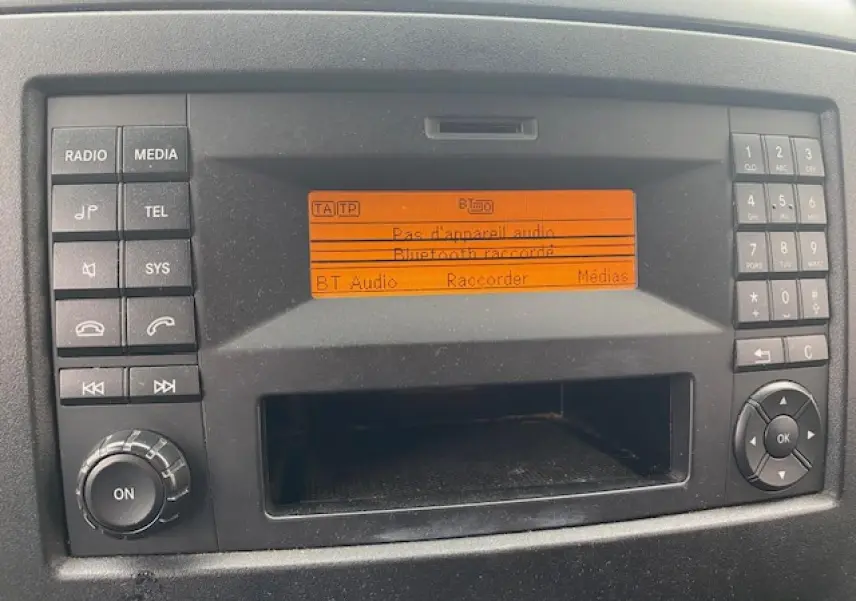 Tableau de bord du Mercedes Sprinter Fourgon 2015 montrant l'autoradio avec écran orange et commandes autour.
