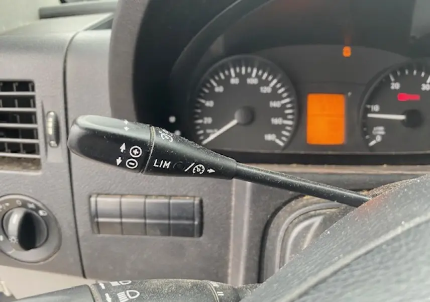 Gros plan sur le commodo de régulateur et limiteur de vitesse du tableau de bord du Mercedes Sprinter blanc de 2015.