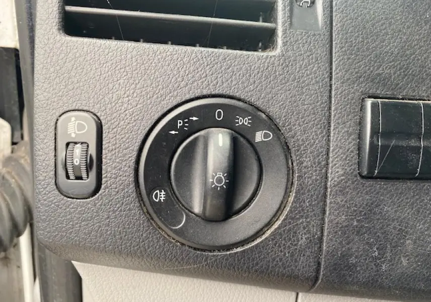 Gros plan sur le bouton de commande des phares du Mercedes Sprinter Fourgon blanc, tableau de bord noir texturé.