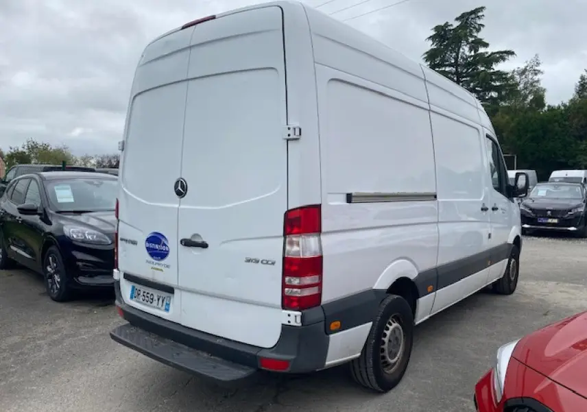 Vue 3/4 arrière droite d’un fourgon Mercedes Sprinter blanc 2015 avec plaques françaises et feux arrière visibles.