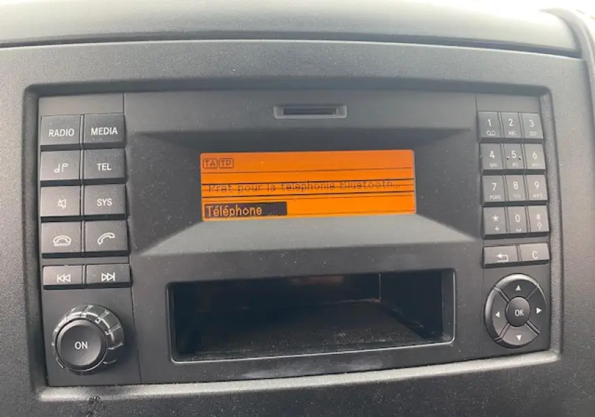 Gros plan sur le tableau de bord du Mercedes Sprinter blanc, affichant l’écran radio avec menu téléphone Bluetooth.