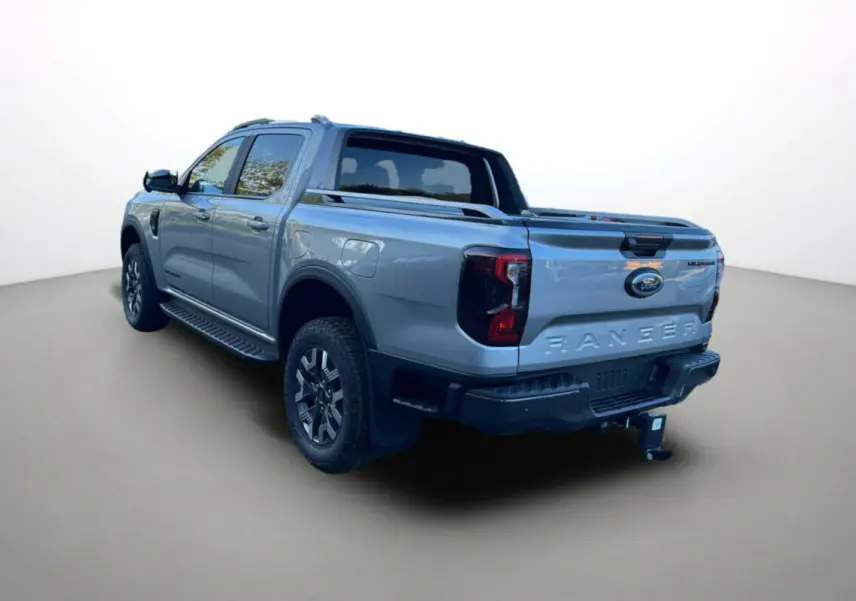 Ford Ranger PHEV gris iconic en 3/4 arrière droit, avec benne, barres de toit et attelage visible.