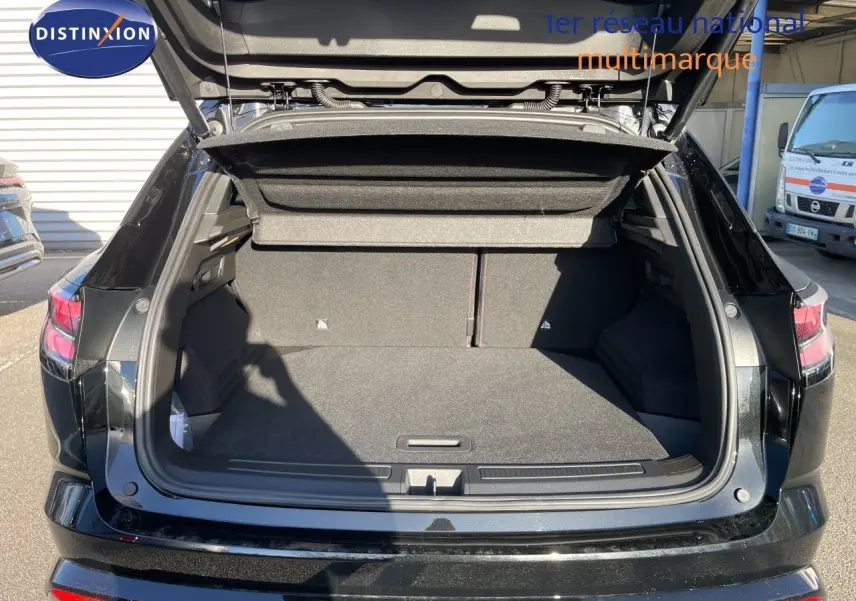 Coffre ouvert en vue arrière d’un Renault Austral noir étoile métal, montrant l’espace de chargement vide et la plage arrière relevée.