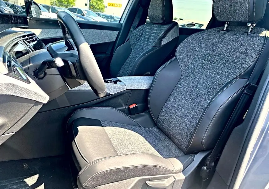 Vue intérieure côté conducteur du Peugeot 5008 Hybrid 145 allure e-dcs6 2025 avec sièges tissu gris et cuir noir.