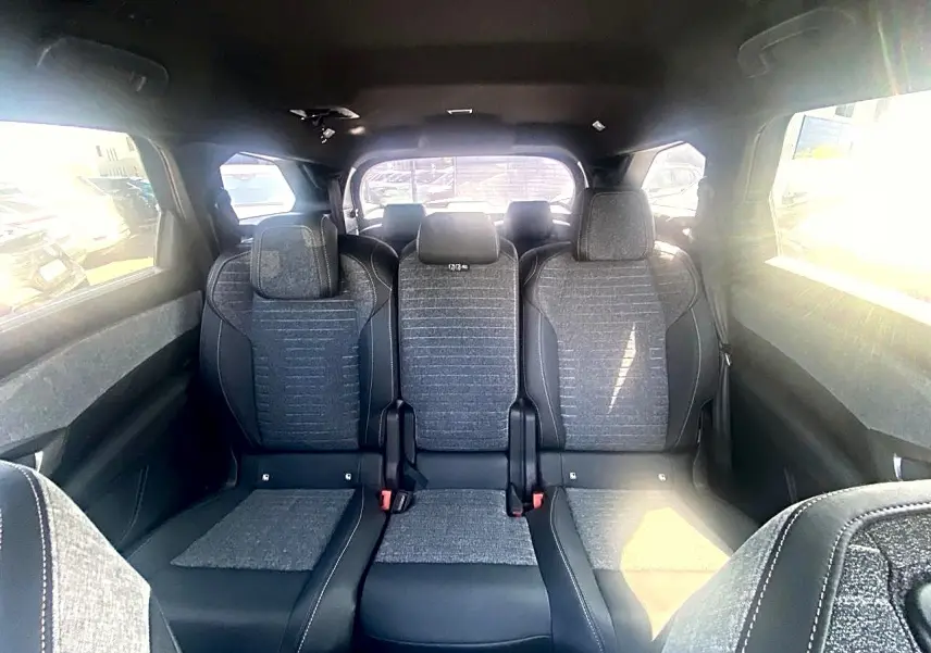 Vue intérieure arrière du Peugeot 5008 Hybrid 145 allure e-dcs6 2025, montrant les trois sièges gris avec appuis-tête.