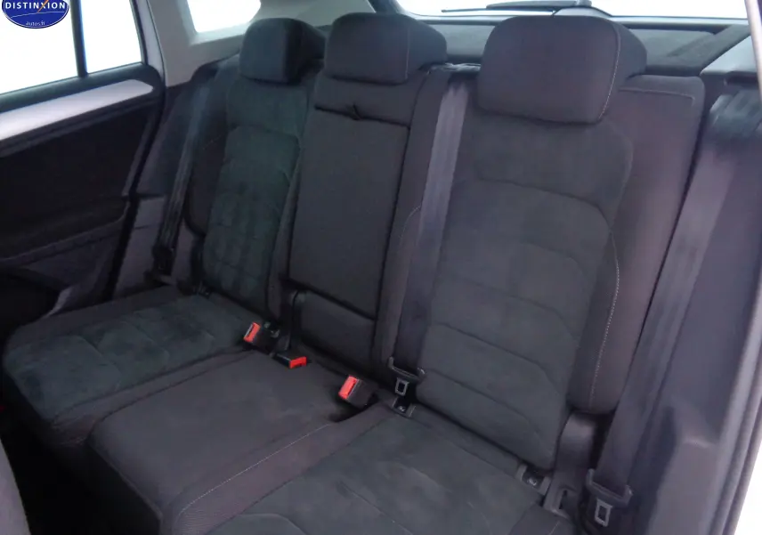 Vue intérieure montrant les sièges arrière en tissu gris foncé du Volkswagen Tiguan blanc 2019, avec ceintures de sécurité visibles.