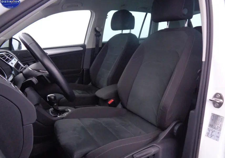 Intérieur du Volkswagen Tiguan blanc 2019, vue côté conducteur montrant sièges noirs et volant avec boîte auto.