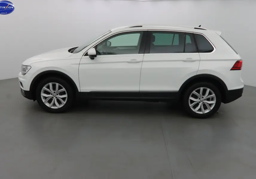 Vue de profil côté gauche d'un Volkswagen Tiguan blanc 2019 avec jantes alliage et protections noires sur les bas de caisse.