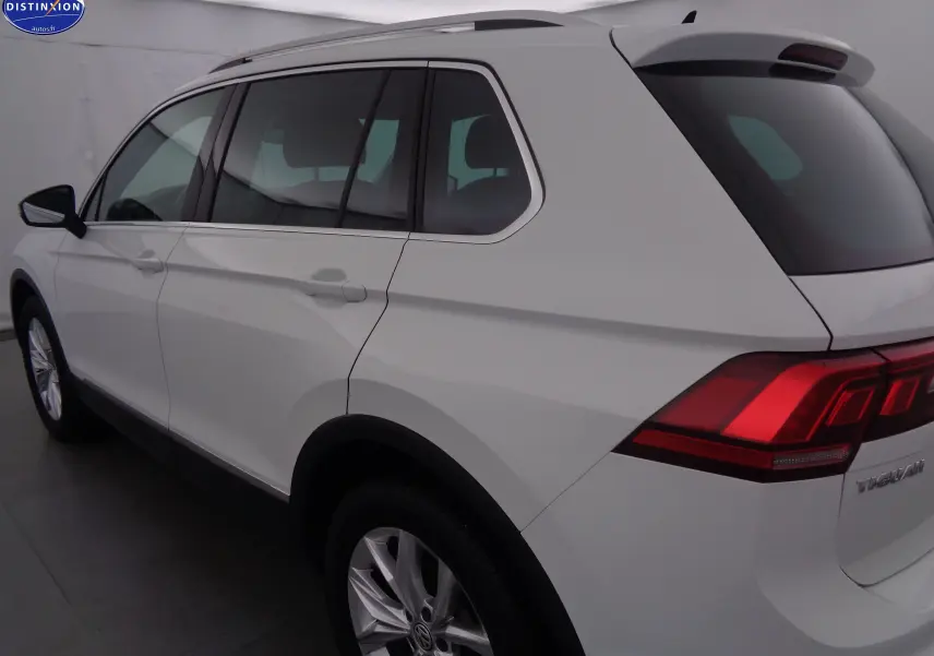 Vue 3/4 arrière côté gauche d'un Volkswagen Tiguan blanc de 2019 avec feux arrière LED et jantes alliage.