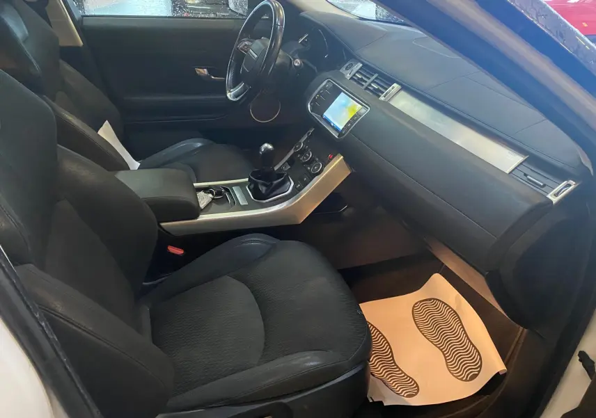 Intérieur noir du Range Rover Evoque 2016 vu côté conducteur, avec tableau de bord et boîte manuelle visibles.