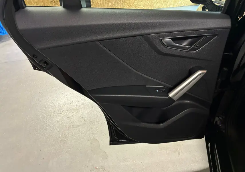 Porte arrière côté droit noire de l'Audi Q2 35 TFSI S-Line 2023 avec poignée argentée et commande de vitre.