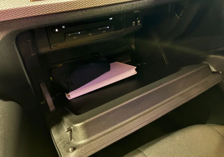 Gros plan sur la boîte à gants ouverte de l'Audi Q2 noire 2023, montrant un livret et un étui à l'intérieur.