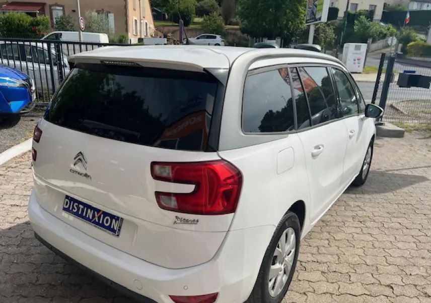Vue 3/4 arrière droite d’un Citroën Grand C4 Picasso blanc avec vitres surteintées et jantes alliage 16 pouces.