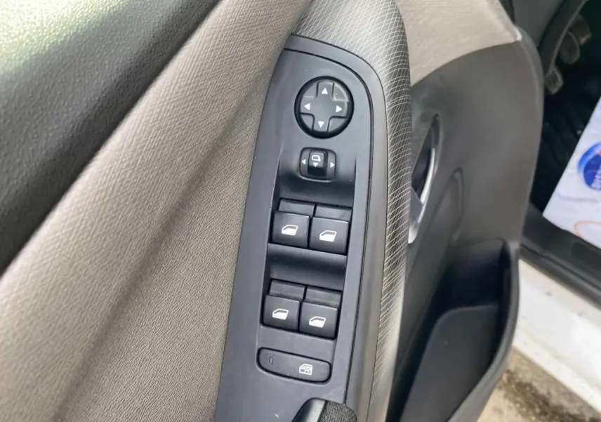 Vue rapprochée de la commande des vitres électriques sur la porte avant gauche d’un Citroën Grand C4 Picasso blanc.