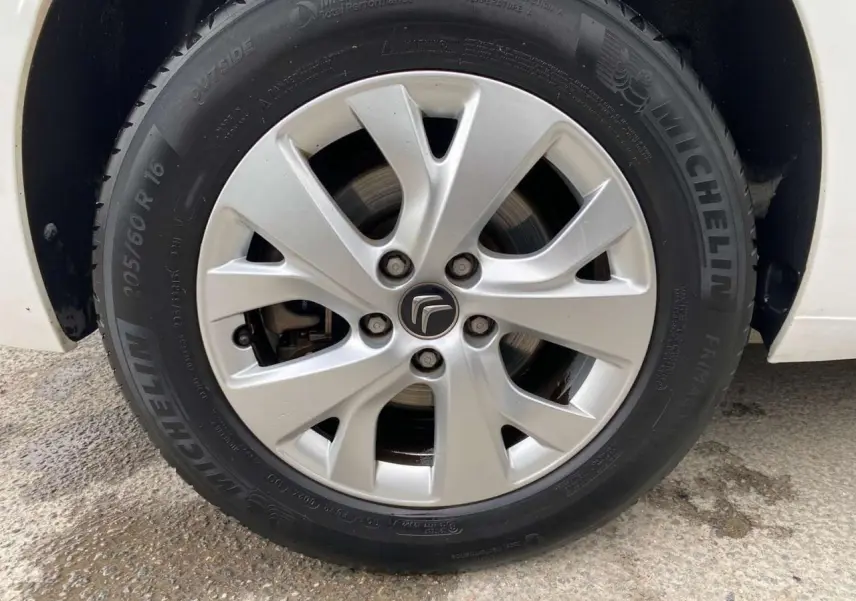 Gros plan sur la jante alliage 16 pouces Notos argentée et pneu Michelin d'un Citroën Grand C4 Picasso blanc.