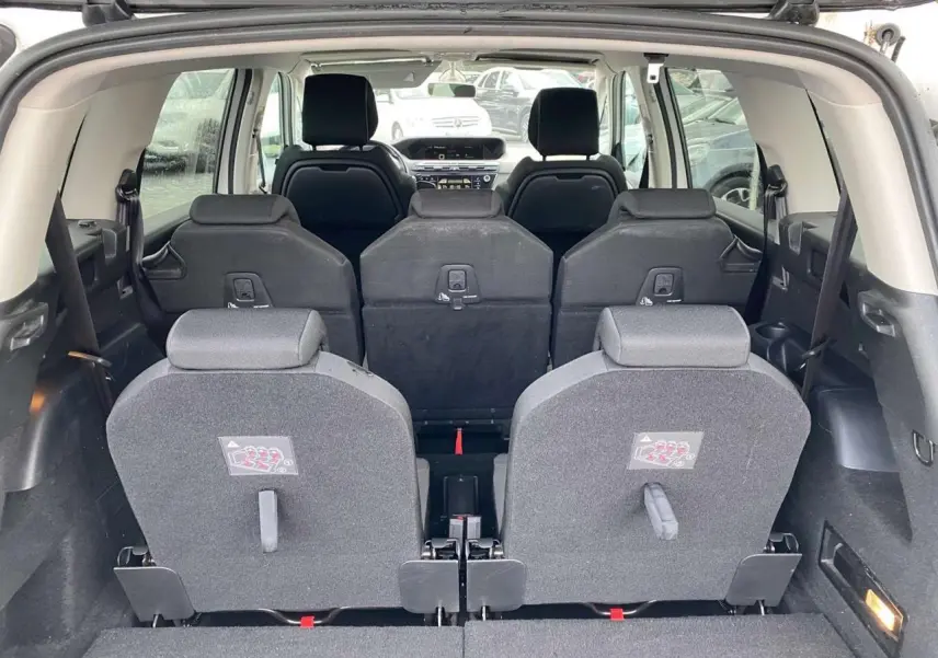 Vue arrière intérieure du Citroën Grand C4 Picasso blanc 7 places, montrant les sièges rabattus et l'habitacle spacieux.