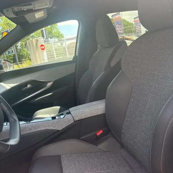 Vue intérieure côté conducteur du Peugeot 3008 Hybrid 136 e-DCS6 Allure 2025, sièges gris tissu et cuir avec console centrale assortie.