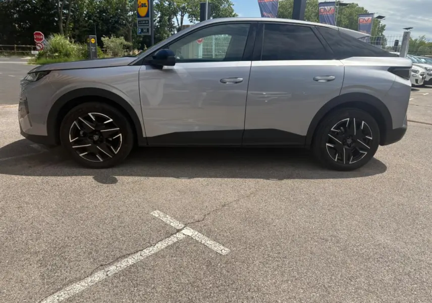Vue de profil côté gauche d’un Peugeot 3008 Hybrid gris clair 2025 avec jantes noires au design moderne.