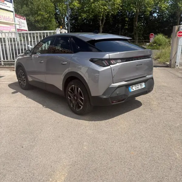 Vue 3/4 arrière droite du Peugeot 3008 Hybrid gris clair 2025 avec toit noir et feux arrière distinctifs.