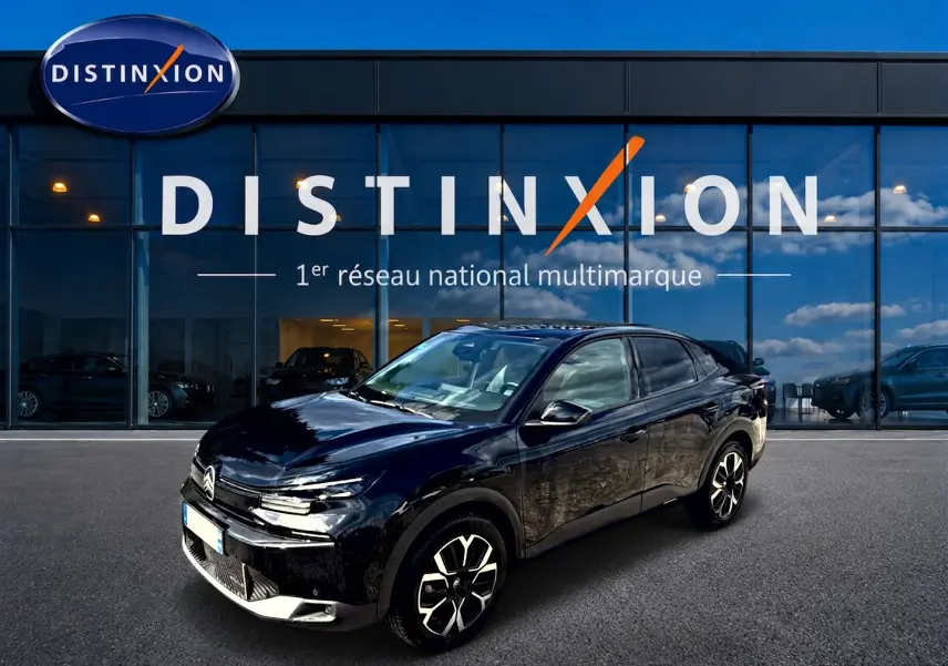 Vue 3/4 avant droit d'une Citroën C4 X noire 2025, avec jantes alu et vitres surteintées devant un showroom Distinxion.