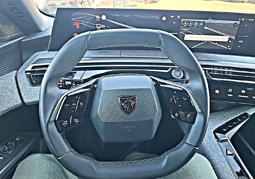 Vue intérieure centrée sur le volant cuir multifonction noir du Peugeot 5008 2025 avec tableau de bord numérique.