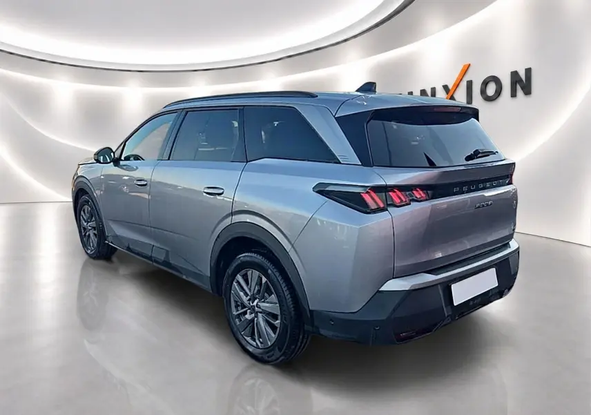 Peugeot 5008 gris artense vue 3/4 arrière droit dans un showroom lumineux avec feux arrière LED distinctifs.