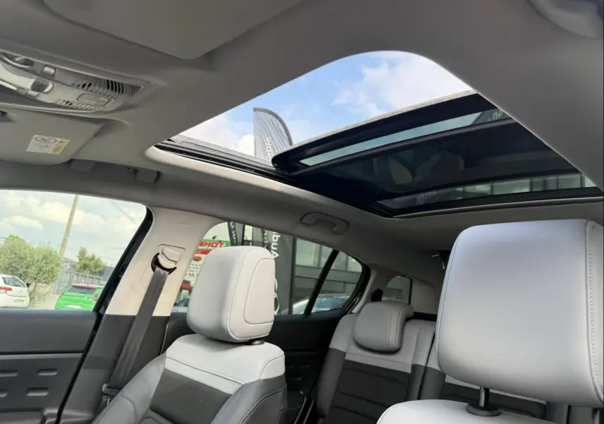 Intérieur du Citroën C5 Aircross 2024 noir métal, vue sur les sièges avant et arrière avec toit ouvrant panoramique ouvert.