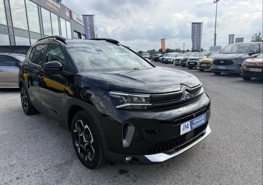 Citroën C5 Aircross noir métal en 3/4 avant droit, avec jantes distinctives et calandre moderne visible.