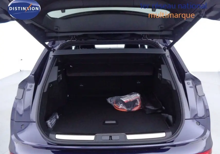 Coffre ouvert vu de l'arrière d'un DS7 Crossback hybride bleu encre métal avec intérieur de coffre noir et accessoires.