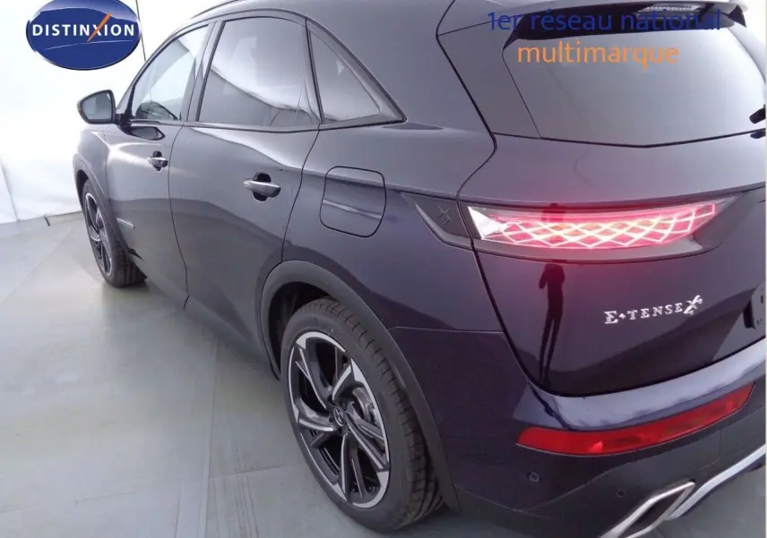 Vue 3/4 arrière droite du DS7 Crossback E-TENSE 300CH en bleu encre métal avec feux arrière LED allumés.