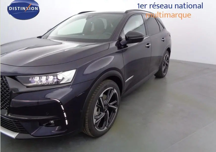 Vue 3/4 avant droit du DS7 Crossback E-TENSE 300CH en bleu encre métal avec ses phares LED allumés et jantes noires.