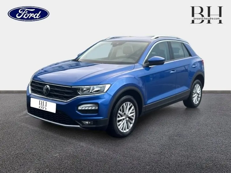 Volkswagen T-Roc bleu Ravenna métallisé vu en 3/4 avant droit avec barres de toit et jantes alu.