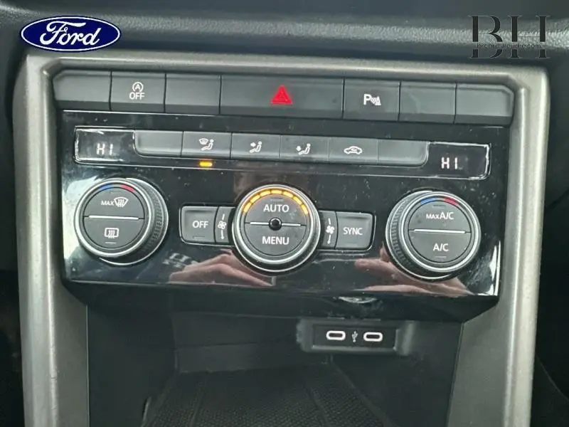 Gros plan sur la console centrale du Volkswagen T-Roc 2021, montrant les commandes de climatisation bi-zone et ports USB.