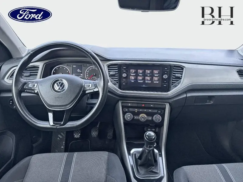 Vue intérieure avant du Volkswagen T-Roc 1.0 TSI 110ch Lounge Business 2021, tableau de bord et volant multifonction noir.