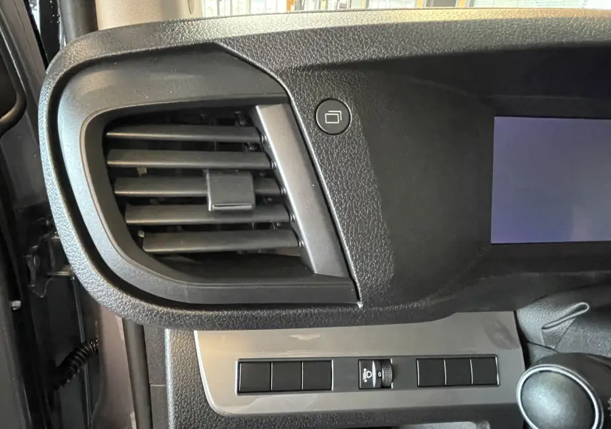 Détail intérieur du tableau de bord côté gauche du Citroën Jumpy Cabine Approfondie gris, avec grille d'aération et commandes.