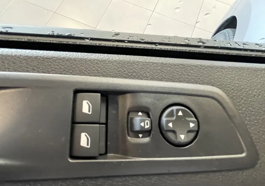 Gros plan sur les commandes de réglage des rétroviseurs et vitres côté conducteur du Citroën Jumpy gris Artense.