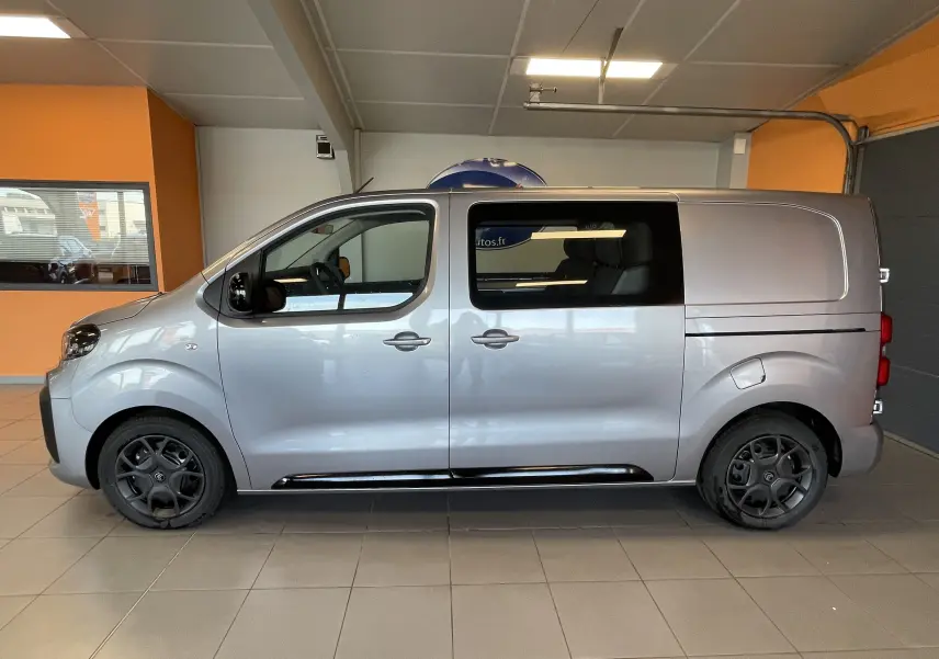 Vue latérale droite d’un Citroën Jumpy cabine approfondie gris Artense avec jantes noires en intérieur showroom.