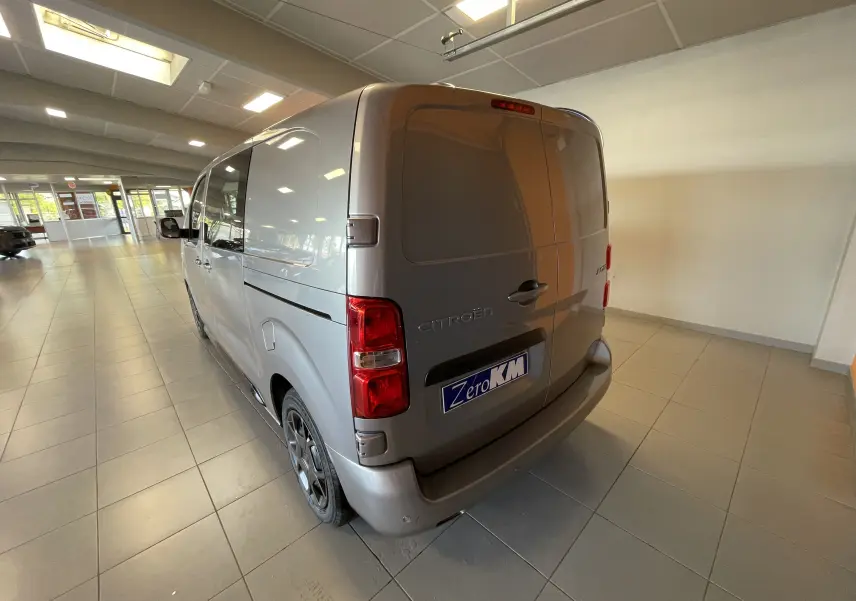 Vue 3/4 arrière gauche d’un Citroën Jumpy Cabine Approfondie gris Artense avec porte latérale coulissante en showroom.