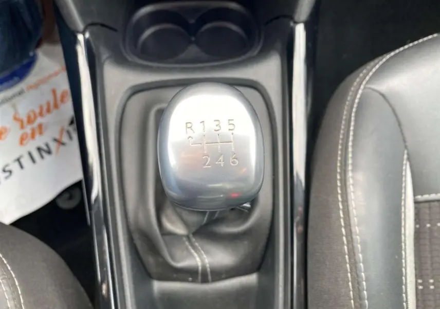 Vue rapprochée du levier de vitesses manuel gris argenté de la Peugeot 2008, entouré de sièges noirs.