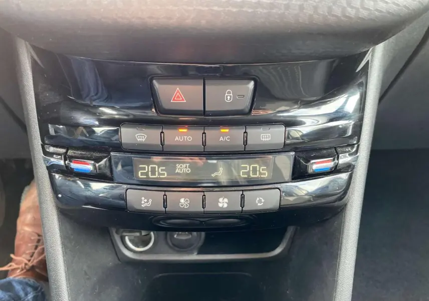 Gros plan sur la console centrale noire brillante du Peugeot 2008 avec commandes climatisation automatique bizone affichant 20,5°C.
